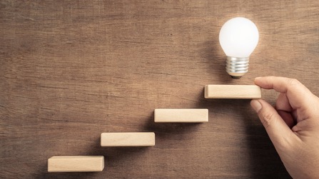 木のブロックでできた階段。一番上には光る電球。成功のイメージ。